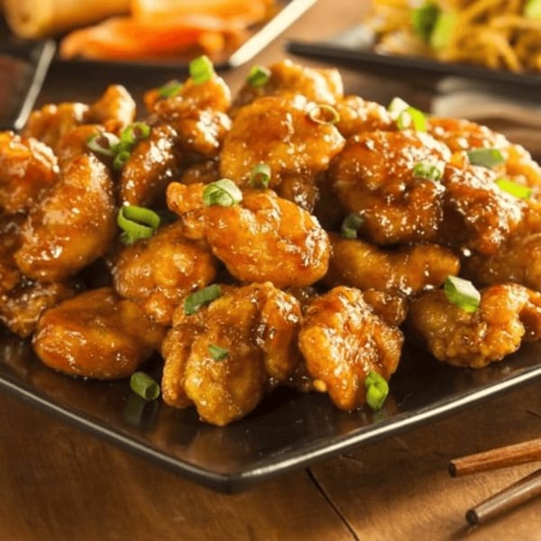A plate of golden-brown General Tso's chicken, garnished with chopped green onions.